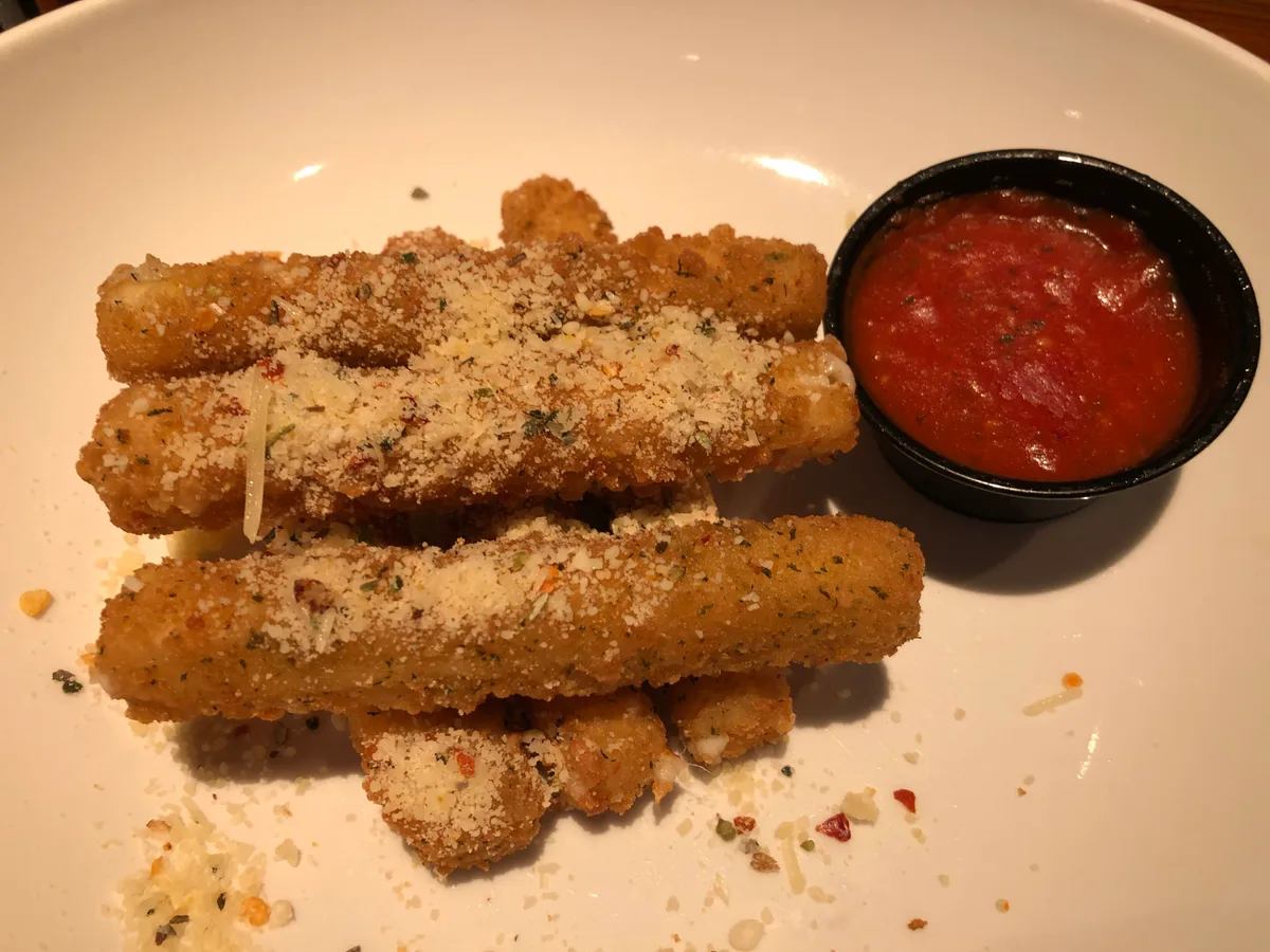 Panierte Käsesticks mit Kräuterpanade und einem Schälchen Tomatendip
