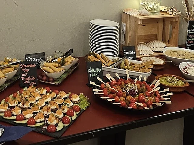 Buffet mit Schwarzbrot-Talern mit Frischkäse und Lachs, Köttbullar-Spießen, Samosas, Frühlingsrollen und Dips auf einer 