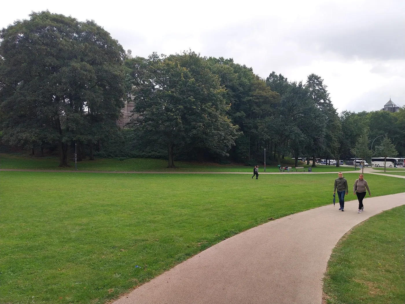 Wiese im Alten Elbpark mit Bäumen und dem Kopf des Bismarckdenkmals dahinter