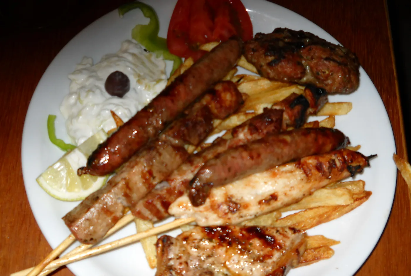 Griechischer Grillteller mit Spießen, Bratwurst, Hacksteak, Pommes und Tzatziki