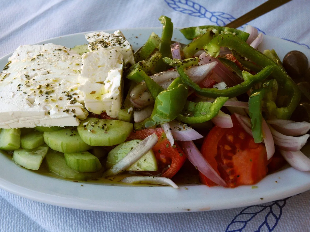 Griechischer Salat mit Fetascheibe, Gurke, Paprika, Tomate, Zwiebeln und Oliven