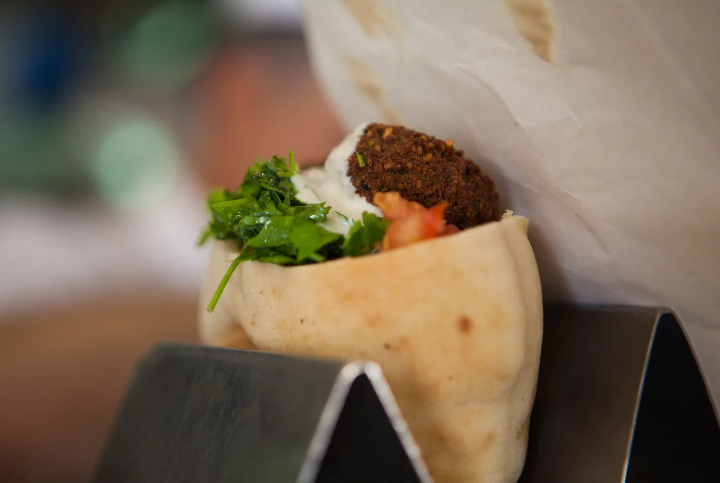 Falafel mit Petersilie, Tomate und Sesamsauce in einem aufgeklappten Fladenbrot