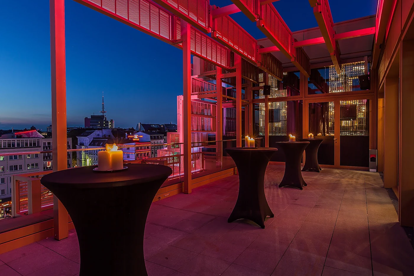 Dachterrasse des GAGA zur blauen Stunde mit Stehtischen, Kerzen, rot beleuchteter Stahlkonstruktion und Blick über St. Pauli