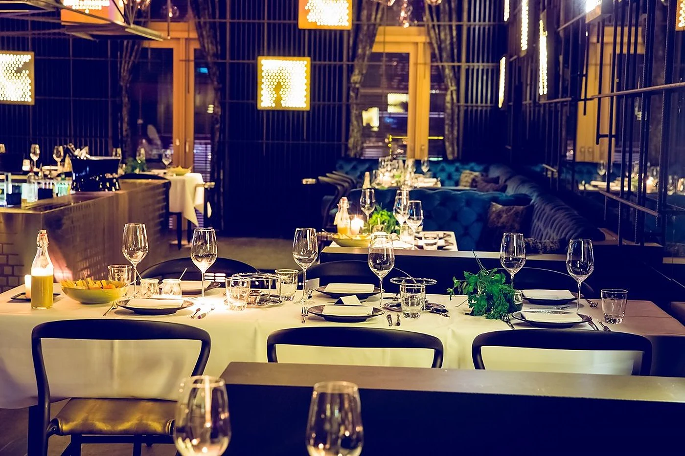 Eingedeckte Tafel im GAGA mit weißem Tischtuch, Weingläsern und blauen Samtbänken im Hintergrund