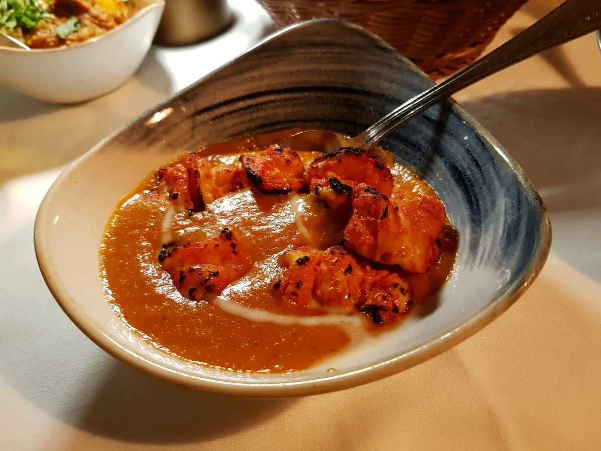 Curry mit Fleischstücken in gelber Sauce mit Koriander in einer Servierpfanne