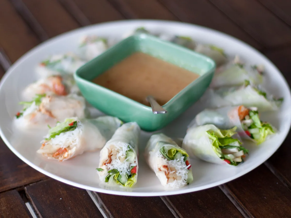 Sommerrollen im Reispapier mit Garnelen, Salat und Reisnudeln, dazu eine Schale Erdnusssauce