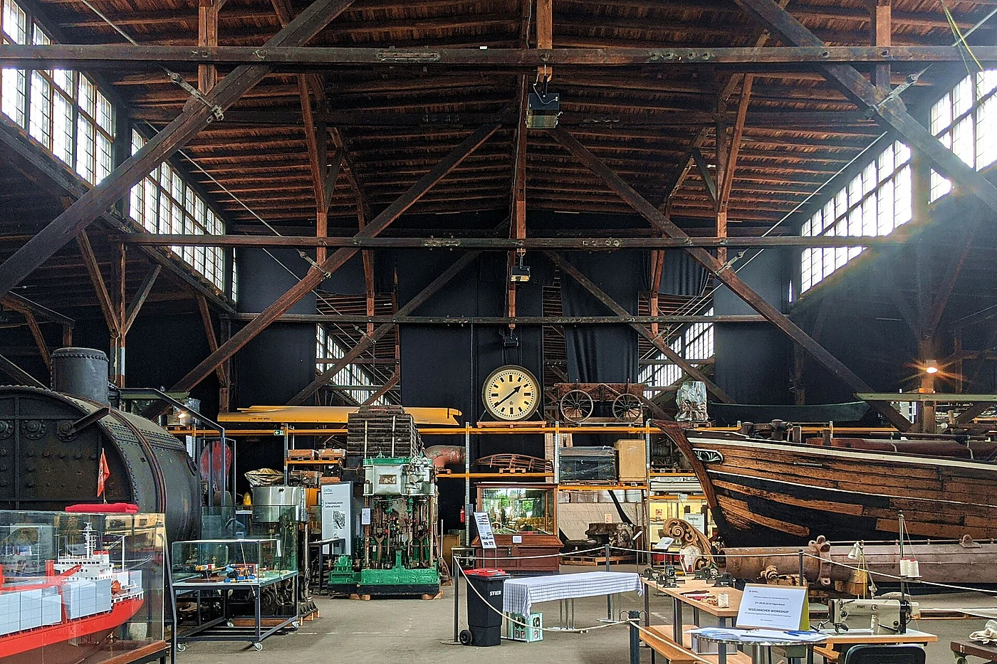 Schaudepot in einem Holzschuppen mit Dachstuhl, Dampfmaschine, Bahnhofsuhr, Vitrinen und Booten