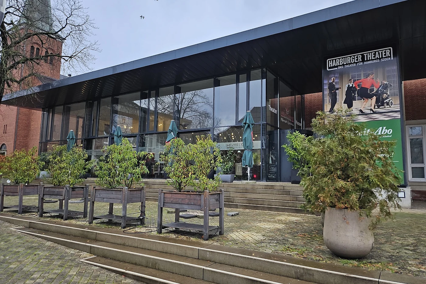 Fassade des Theaters mit Fensterfront und Bänken davor