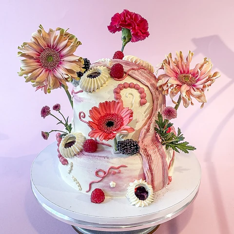 Weiße Torte mit rosa Verzierungen, Beeren und frischen Gerbera- und Nelkenblüten