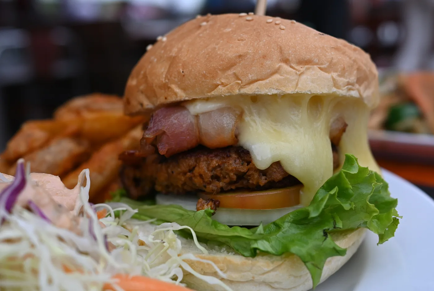 Burger mit knusprigem Hähnchen-Patty, geschmolzenem Käse, Bacon, Salat und Tomate im Sesambrötchen