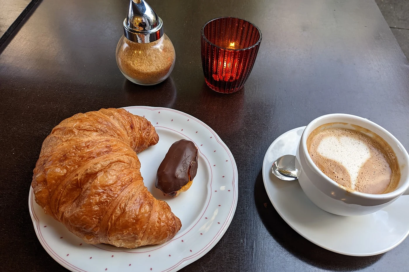 Croissant und Gebäck neben einem Cappuccino