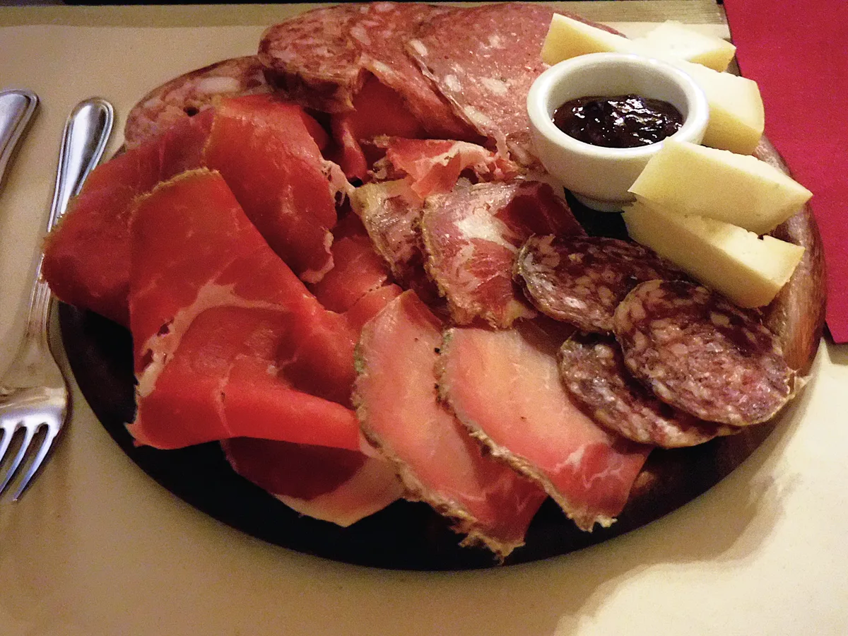 Holzbrett mit Schinken, Salami, Käse, Oliven und Brot