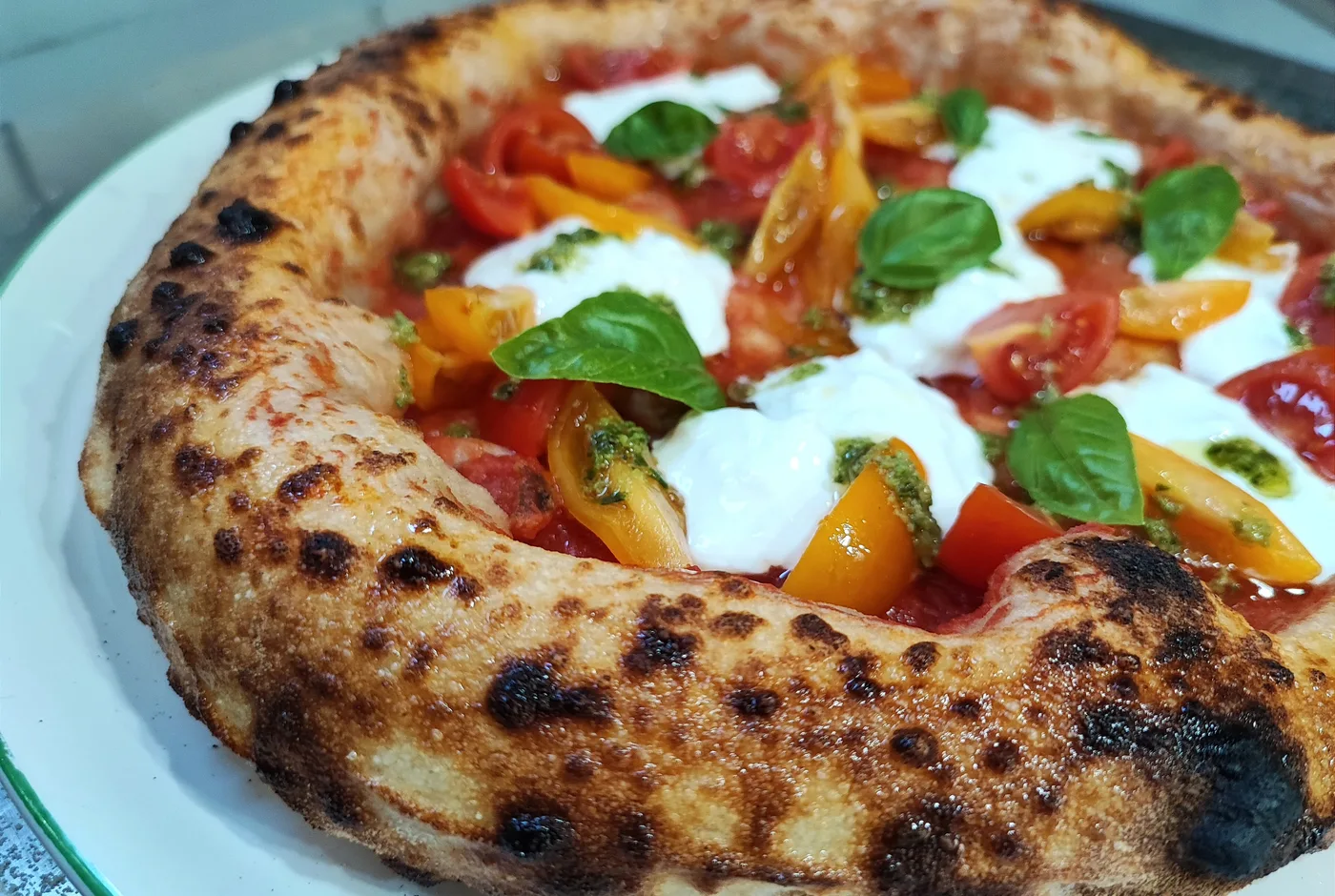 Neapolitanische Pizza mit hohem Rand, Tomaten, Stracciatella und Basilikum