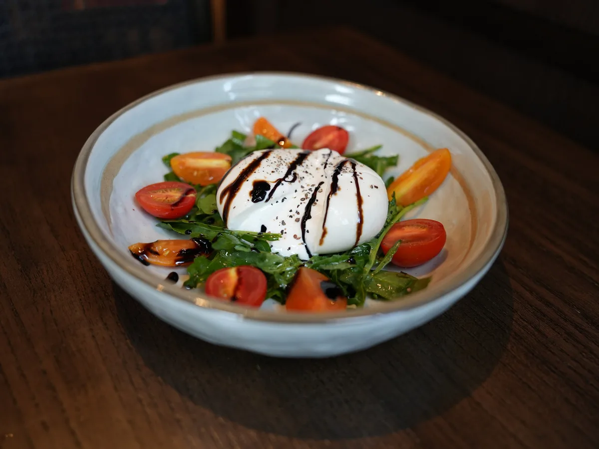 Burrata mit Rucola, Kirschtomaten und Balsamico in einer hellen Schale
