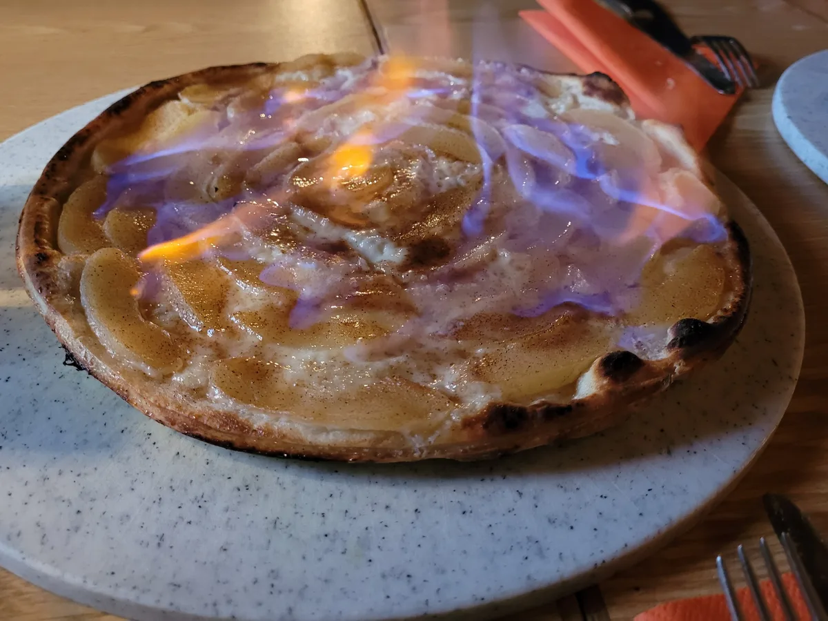 Süßer Flammkuchen mit Apfelscheiben und Zimt, mit blauer Flamme flambiert