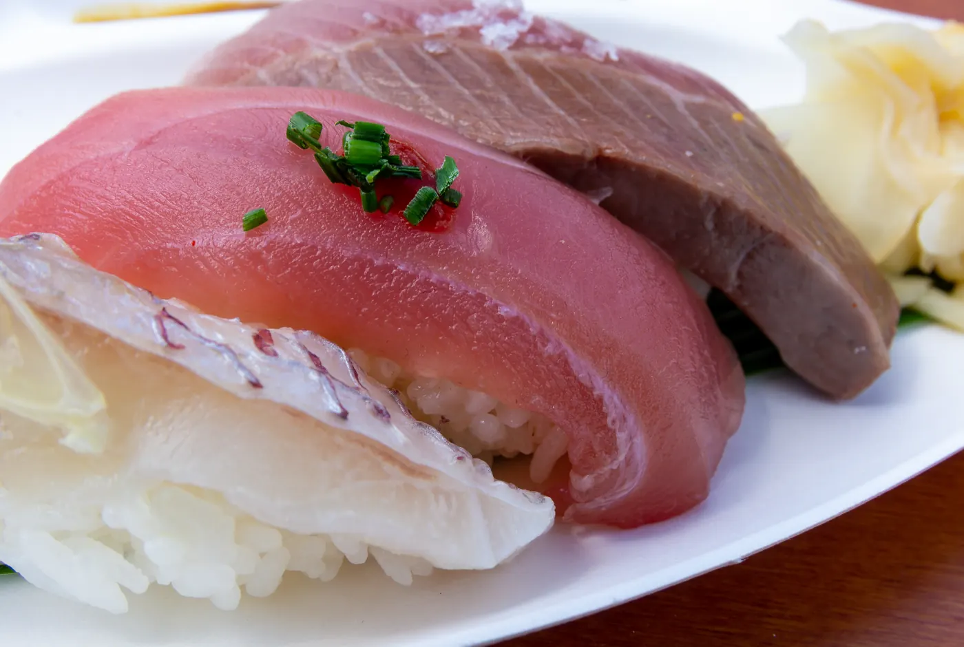 Nigiri-Sushi mit Thunfisch und weißem Fisch auf einem Teller, daneben eingelegter Ingwer
