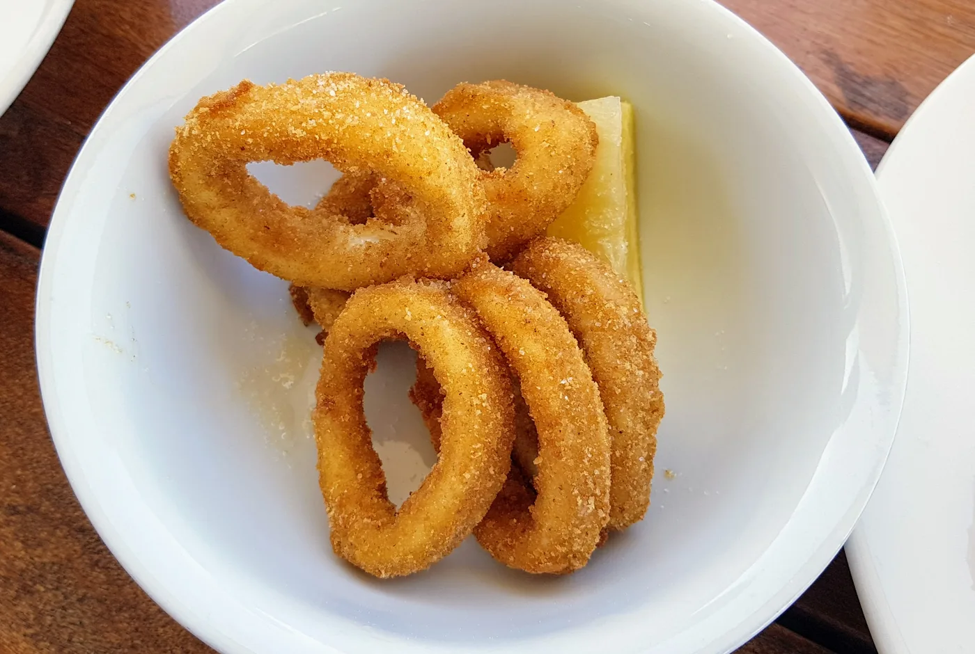 Frittierte Calamariringe mit Zitrone in einer weißen Schale