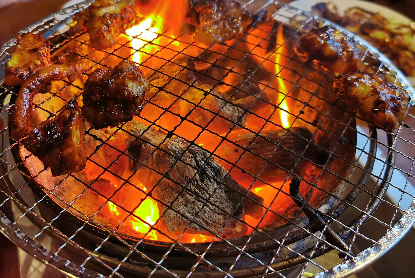 Tischgrill mit glühender Kohle und mariniertem Fleisch auf dem Rost