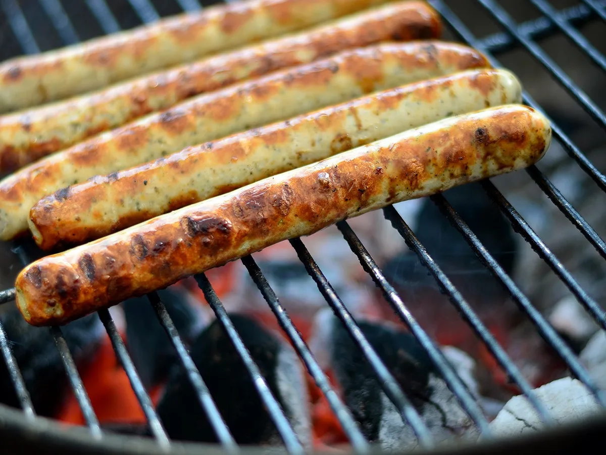 Mehrere Bratwürste auf dem Rost eines Holzkohlegrills
