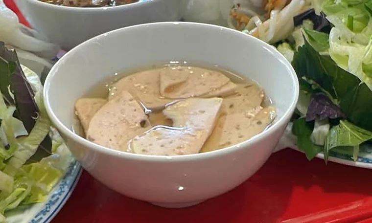 Schale mit Fischsauce und vietnamesischer Wurst, daneben Salat und Kräuter