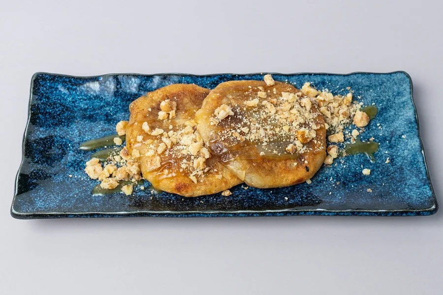 Zwei gefüllte Hotteok-Pancakes mit Walnüssen, Zimt und Zucker auf blauem Teller