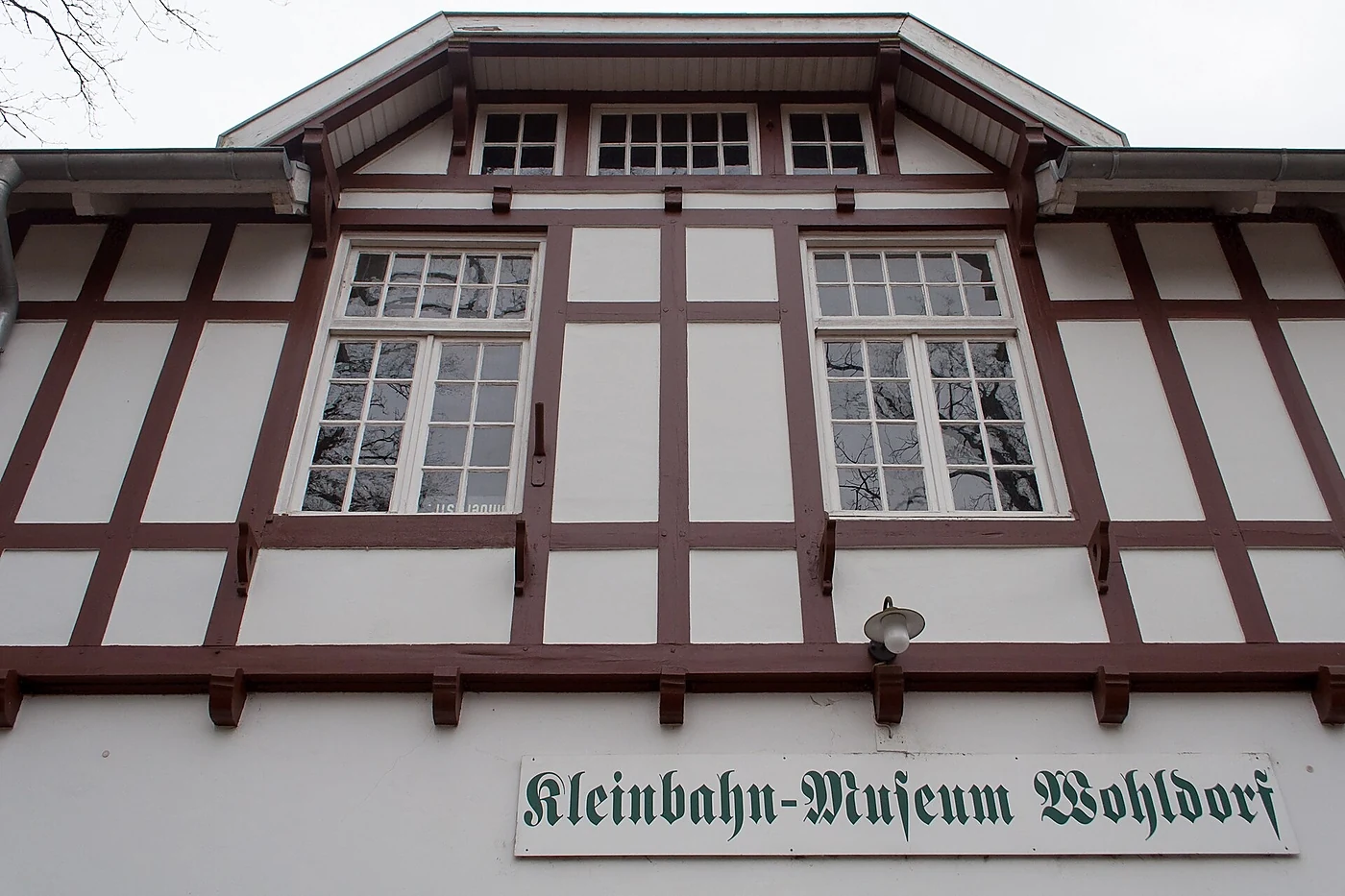 Fachwerkgiebel des Museums mit weißen Gefachen, braunen Balken und dem Schild „Kleinbahn-Museum Wohldorf“ in Frakturschr