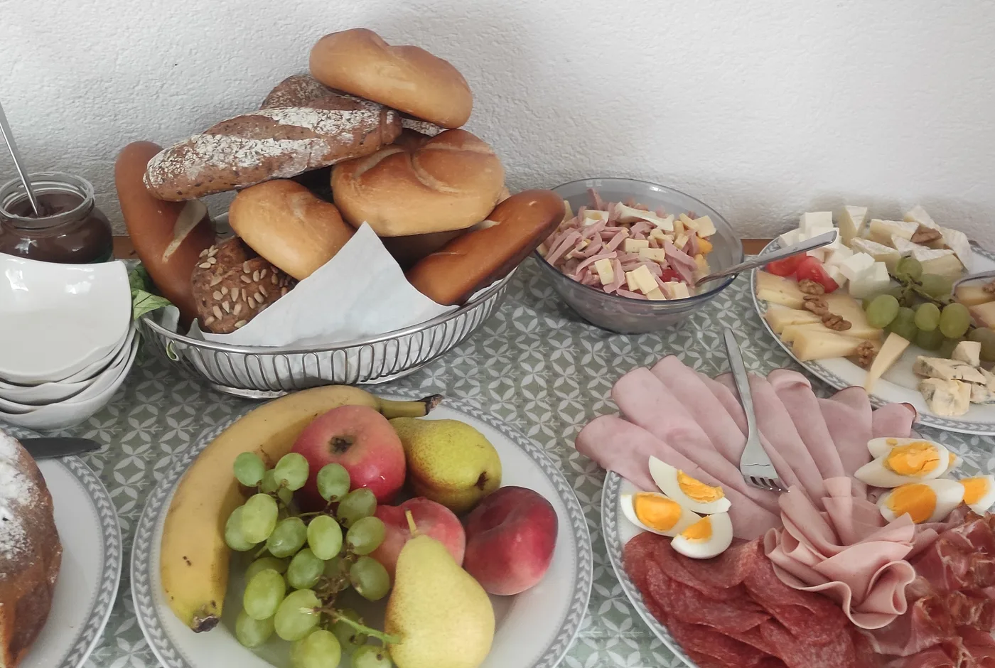 Frühstückstafel mit Brötchen, Brot, Käse, Aufschnitt, Eiern und Obst