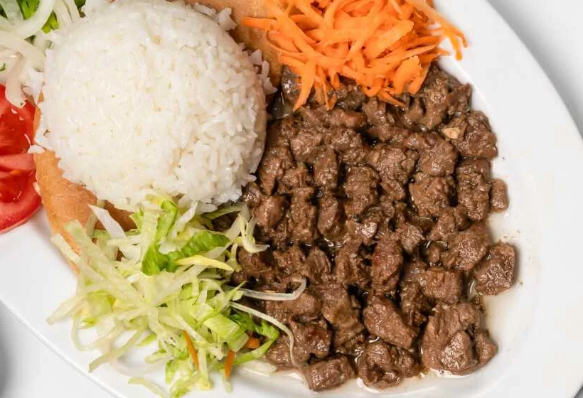 Gewürfeltes Rindfleisch vom Grill mit Reis, Salat und Möhren auf ovalem Teller