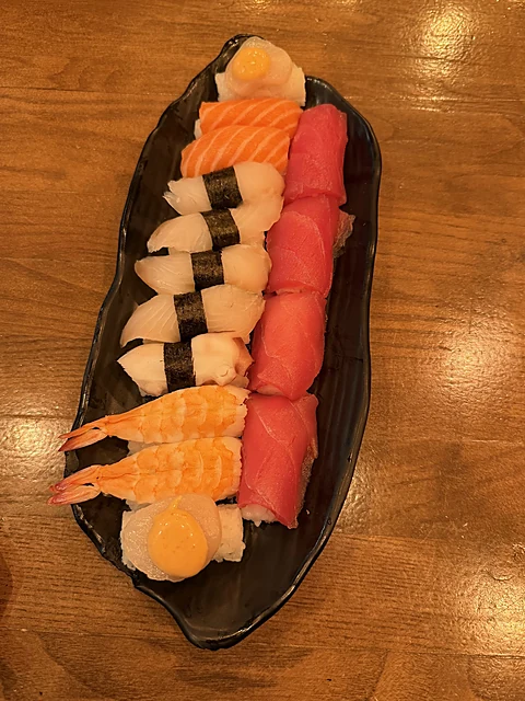 Sushi-Platte mit Nigiri und Sashimi auf einem schwarzen Bootsteller