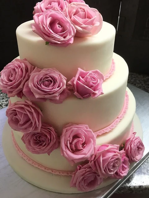Dreistöckige weiße Hochzeitstorte mit rosa Zuckerrosen