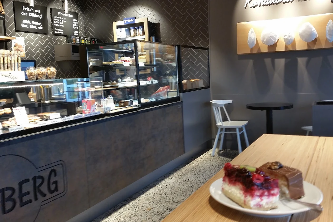 Verkaufsraum mit dunkler Theke und Kuchenstück