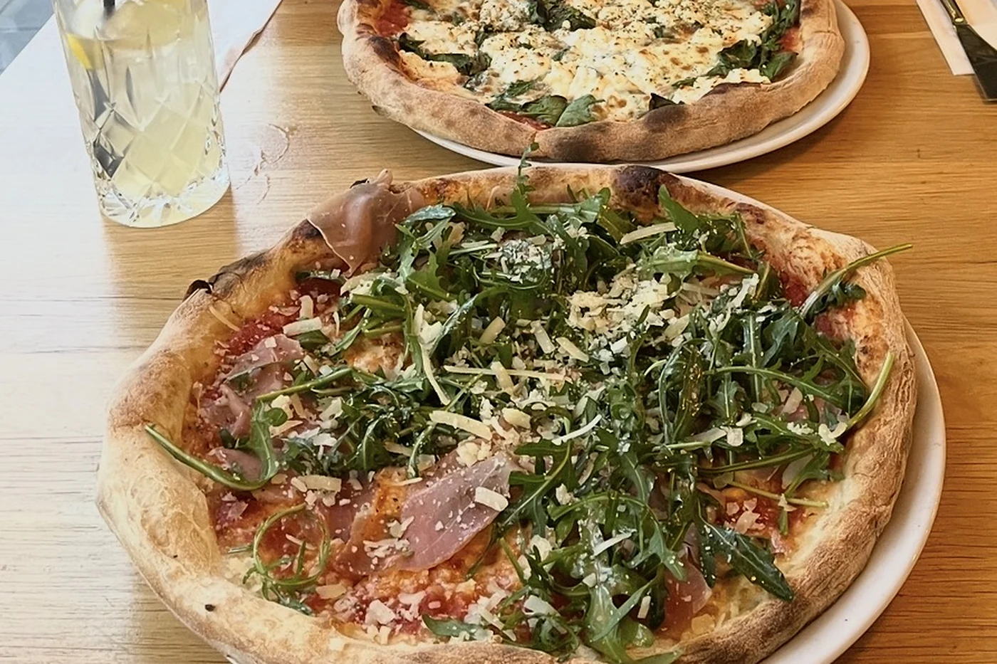 Zwei Pizzen mit Rucola auf einem Holztisch
