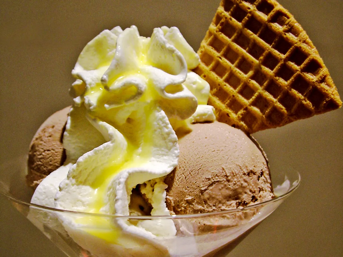 Eisbecher mit Schokoladenkugeln, Sahnehaube und einer Waffel im Glas