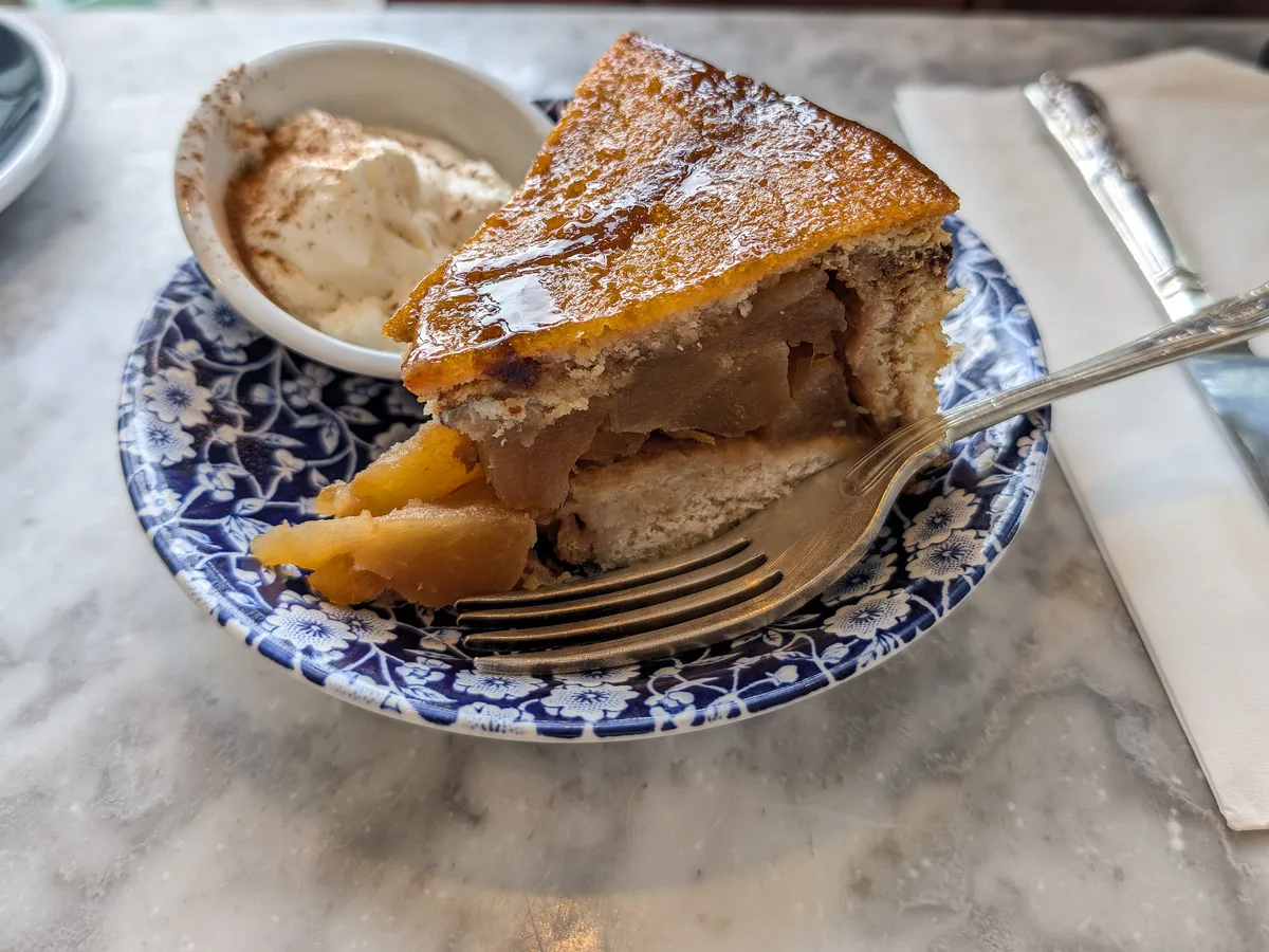 Stück Apfelkuchen mit Sahne auf einem blau gemusterten Teller