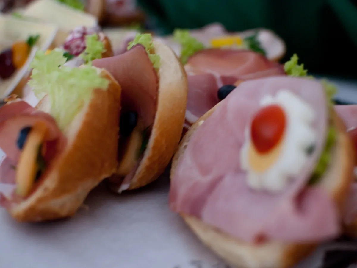 Belegte Brötchen mit Schinken, Käse, Salat und Tomate auf einer Platte