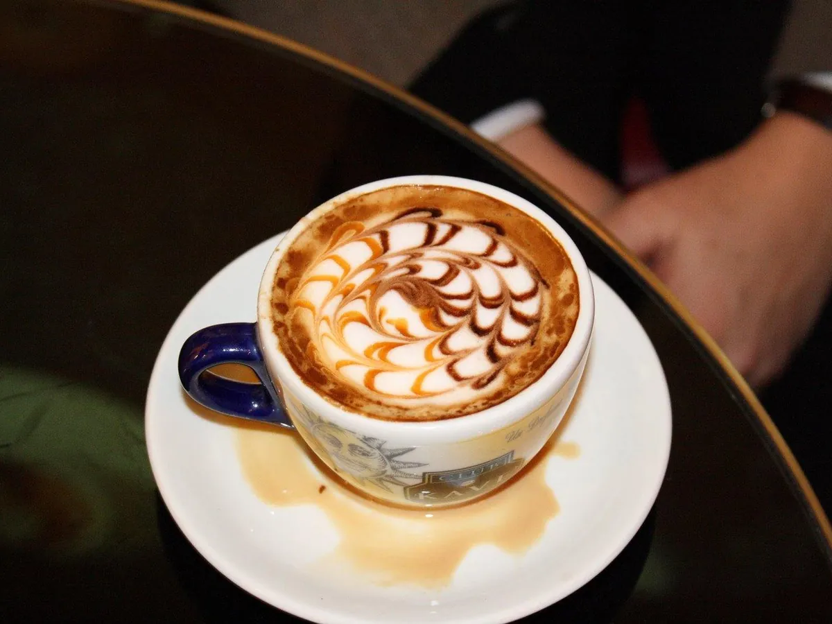 Cappuccino mit Muster im Milchschaum in einer Tasse auf einer Untertasse