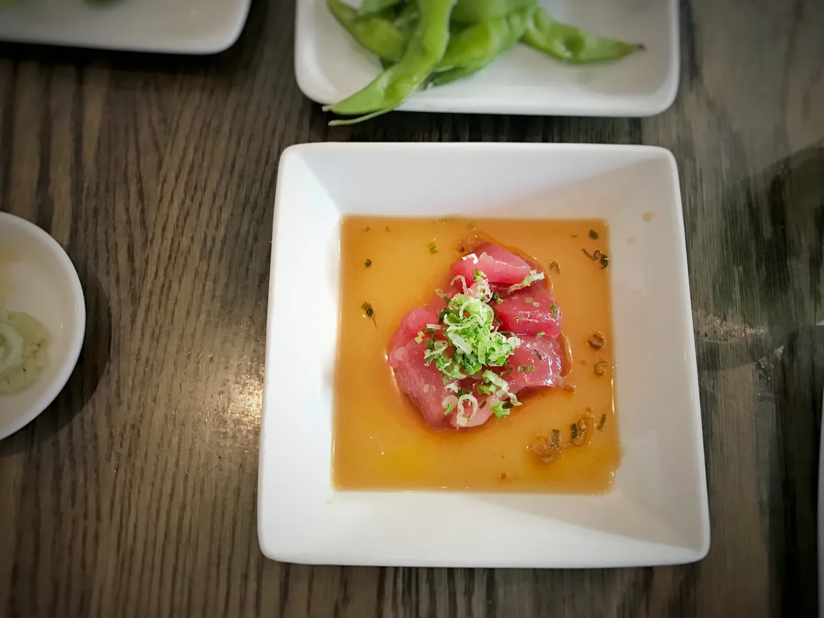 Dünn geschnittener roher Thunfisch in Marinade auf einem weißen Teller