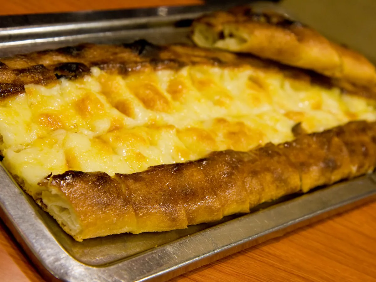 Mit Käse belegtes Pide auf einem Metallblech