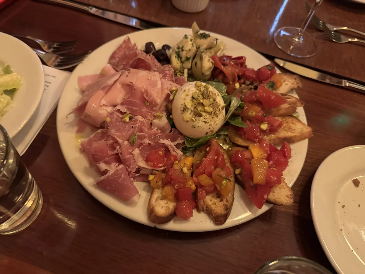 Platte mit Schinken, Salami, Burrata, Oliven und belegten Brotscheiben