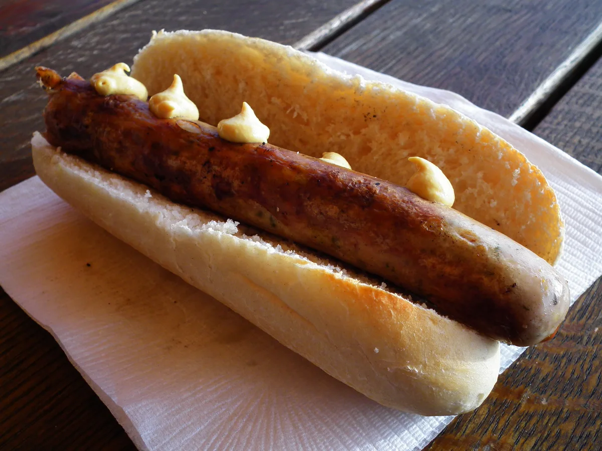 Gegrillte Thüringer Bratwurst mit Senf in einem aufgeschnittenen Brötchen