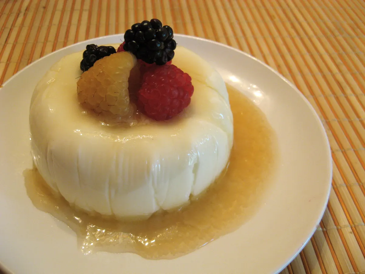 Panna cotta mit Beeren und Sauce auf einem weißen Teller