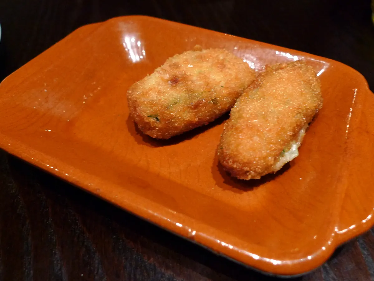 Zwei goldbraune Kroketten auf einer Tonschale
