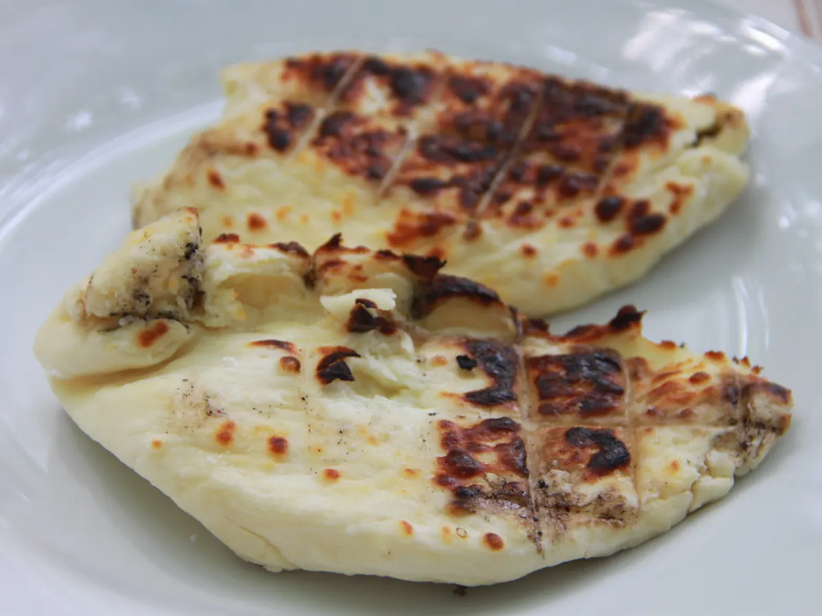 Zwei Scheiben gegrillter Halloumi mit Grillstreifen auf einem weißen Teller