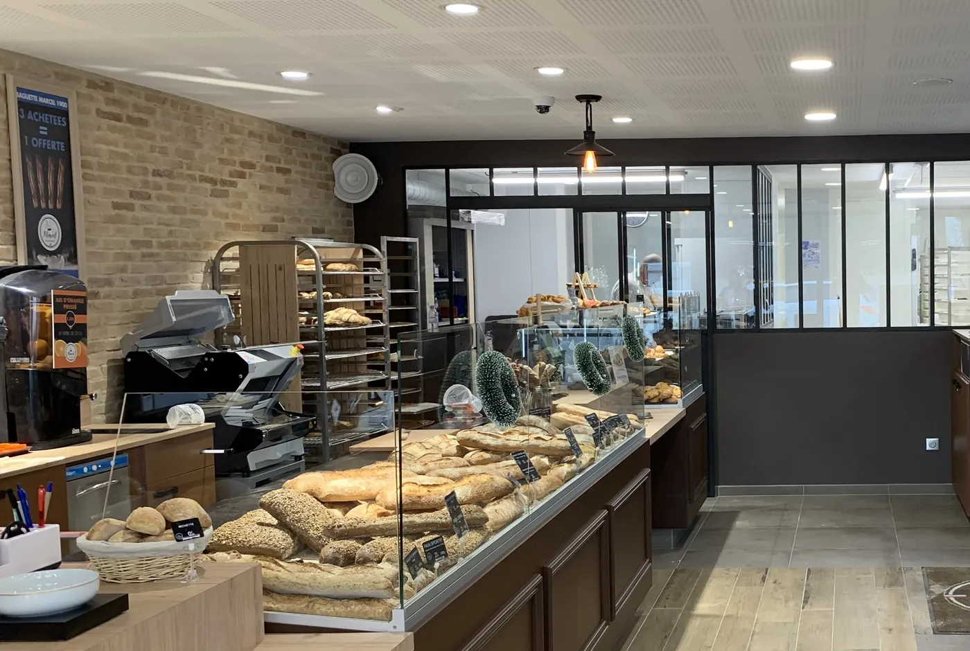 Bäckereitheke mit Baguettes und Brotlaiben in einer Glasvitrine, dahinter Backbleche in einem Regal