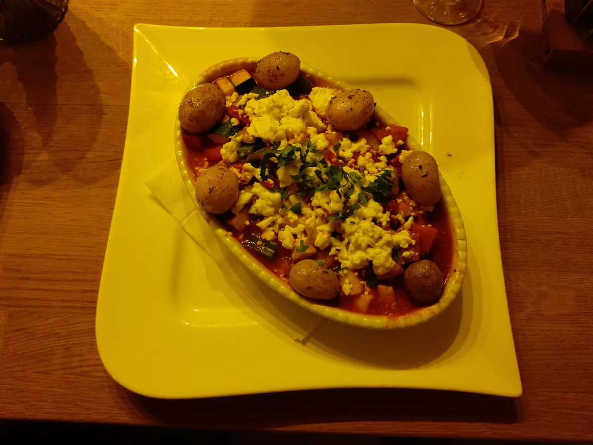 Ratatouille aus Zucchini, Paprika und Tomaten mit zerbröseltem Käse und kleinen Kartoffeln in einer Auflaufform