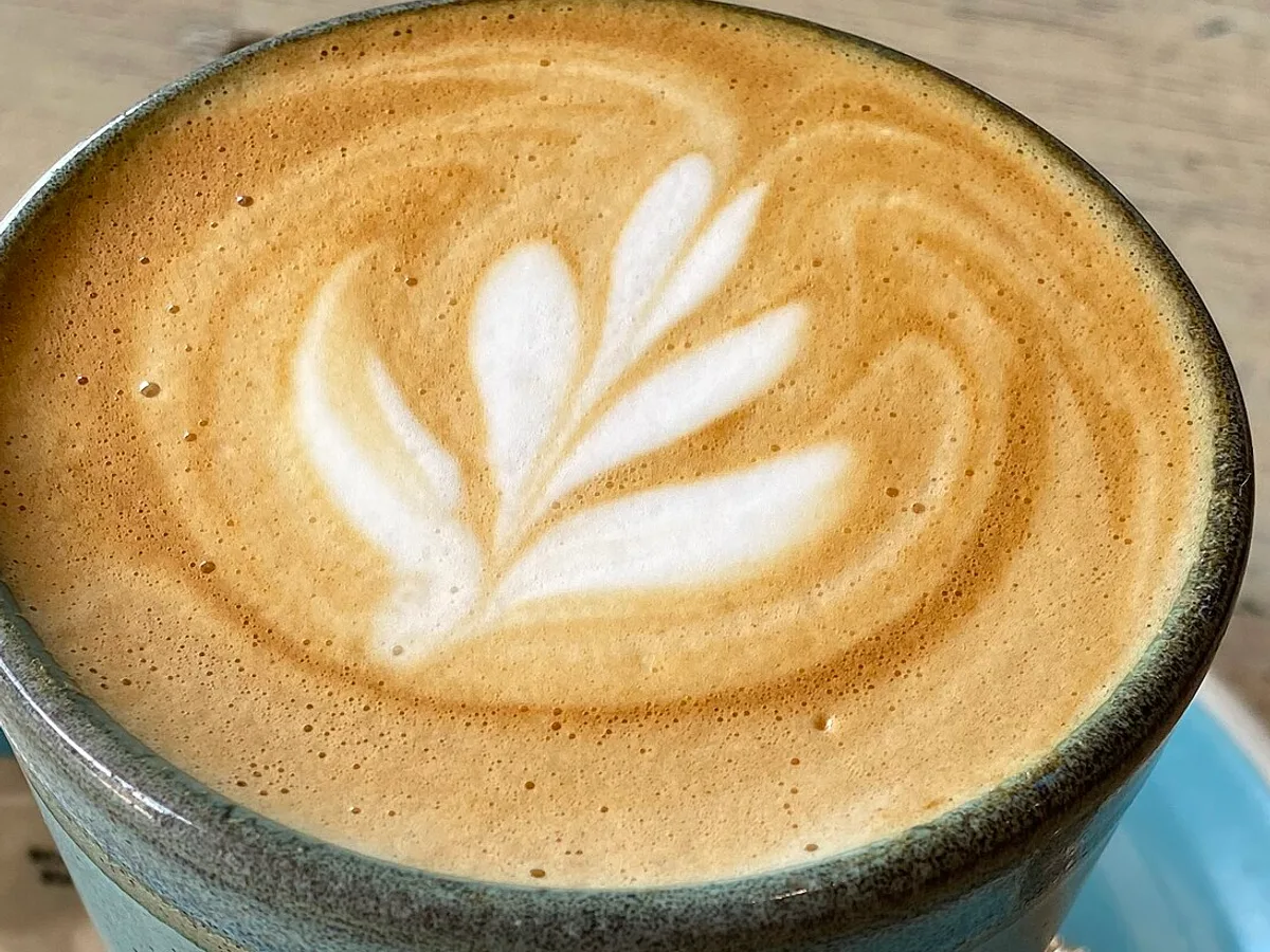 Flat White mit Milchschaummuster in einer Keramiktasse auf einer hellblauen Untertasse