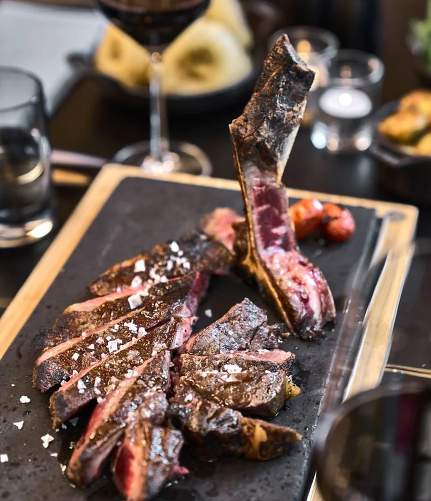 Aufgeschnittenes T-Bone-Steak mit Meersalz auf heißem Stein, dazu Rotwein