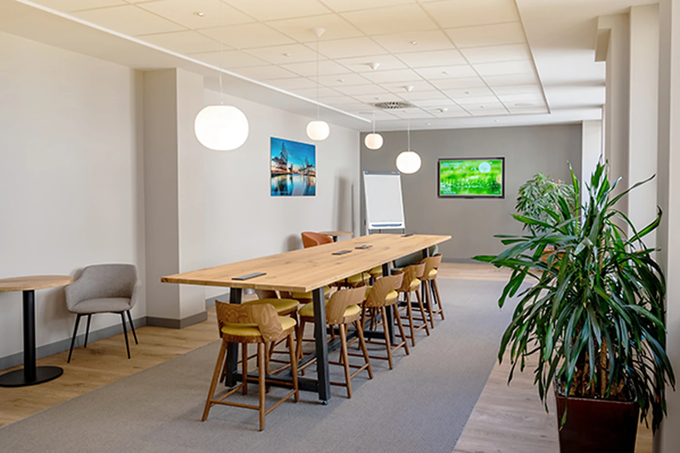 Lounge mit langem Holztisch, Barhockern und Pflanzen
