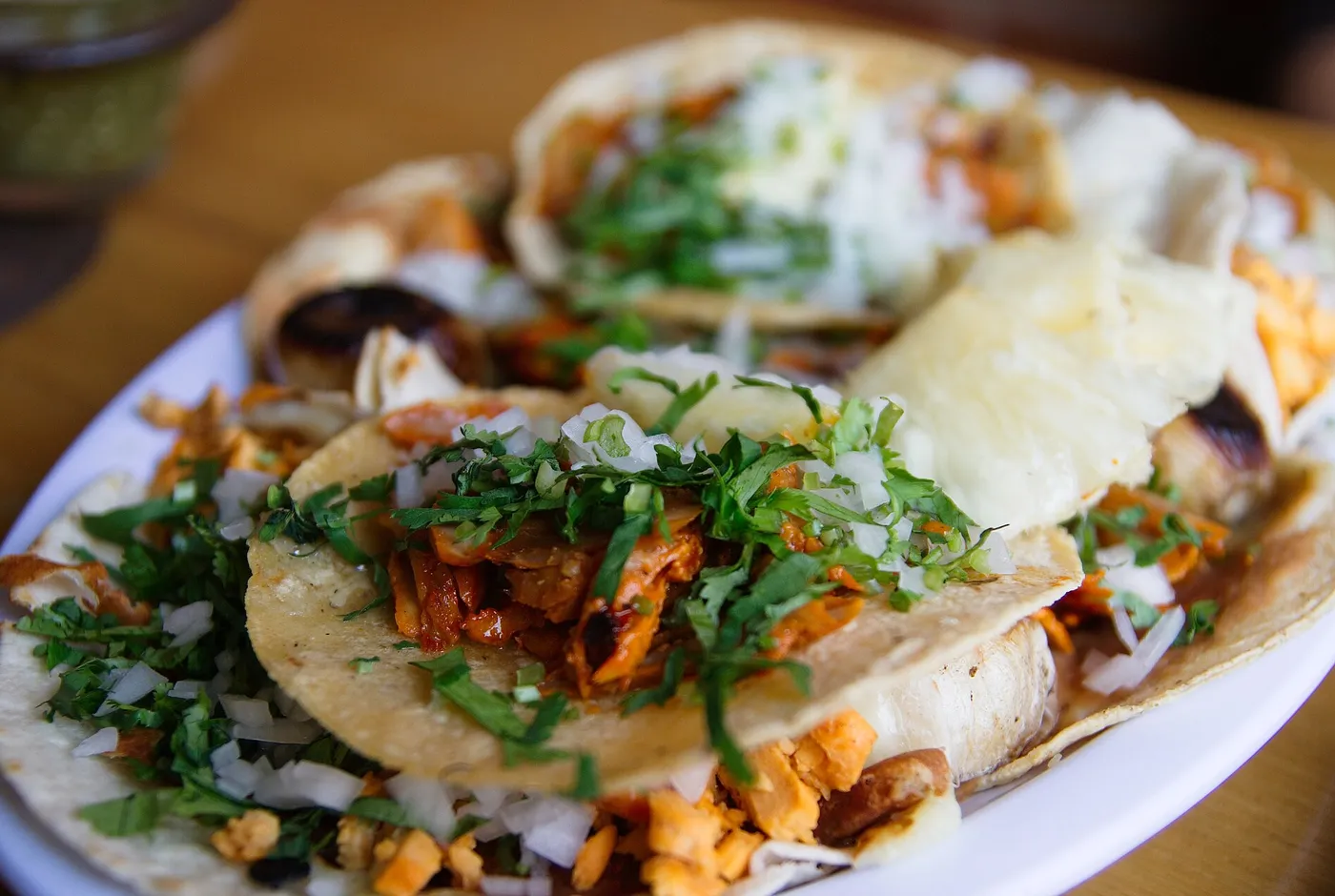 Mehrere Tacos al Pastor mit Fleisch, Zwiebeln und Koriander auf einem Teller