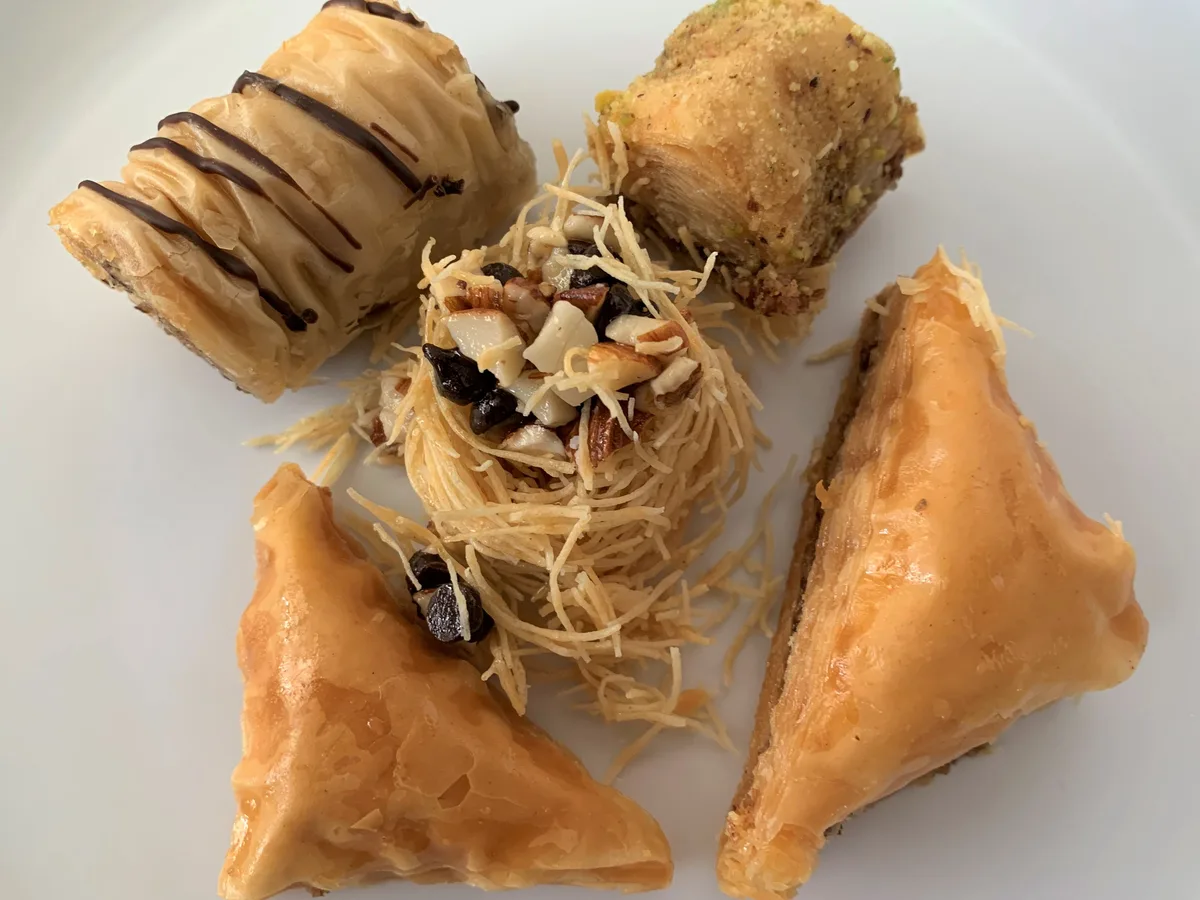Verschiedene Baklava-Stücke mit Nüssen und Pistazien auf einem weißen Teller